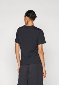 T-shirt noir en coton à manches courtes et col rond, avec un design simple sans logos ni motifs visibles.