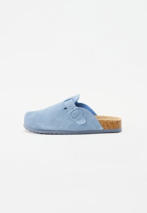 Blauwe leren klomp met een gespsluiting, kurken voetbed, ronde neus en een gestructureerde rubberen zool. Eenvoudig ontwerp met minimale accenten.