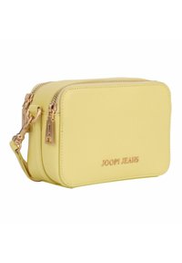 Bolso bandolera amarillo con textura y herrajes dorados, con cierre de cremallera y marca en relieve. Forma rectangular compacta.