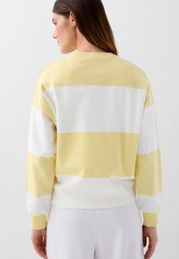 Maglione a righe gialle e bianche, in cotone, con collo a giro e polsini e orlo a costine, vestibilità rilassata. Texture liscia, design informale.