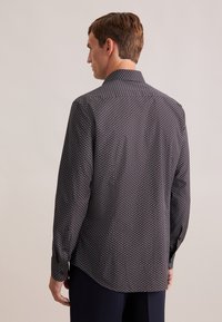 Langemouwen shirt gemaakt van geweven stof, met een donkerblauwe achtergrond en kleine cirkelvormige patronen in lichte kleuren, en een klassieke kraag.