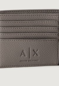 Pilkos tekstūruotos odos kortelių laikiklis su septyniais horizontaliais kortelių skyreliais ir iškilmiu „A|X Armani Exchange“ logotipu apatiniame centre.