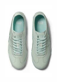 Světlé mátově zelené tenisky vyrobené z hladké kůže, s oblámi tvary, šesti otvory na šňůrky a texturovanou gumovou podešví.