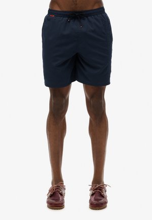 Pantaloni da bagno blu navy con vita elastica e cordoncino, dotati di tasche laterali e logo testurizzato sul davanti.
