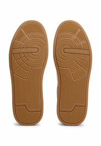 Suola di scarpa in gomma di colore kaki con un battistrada decorato e "TOMMY HILFIGER" impresso. Presenta design circolari e a spina di pesce per una migliore aderenza.