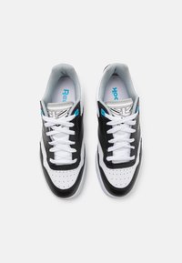 Svarta och vita sneakers med genombruten tåkapp, vita snören och ljusgrå detaljer. Har en blå logotyp på innersulan och sidan.