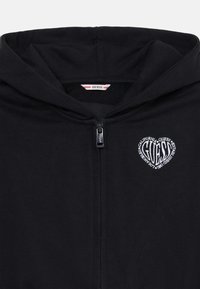 Black zip-up hoodie featuring a heart-shaped embroidered logo in white, with a drawstring hood and soft cotton material.