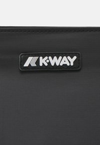 Black K-WAY bag featuring a textured surface with a prominent logo tag, stitched detailing, and a minimalist rectangular shape.