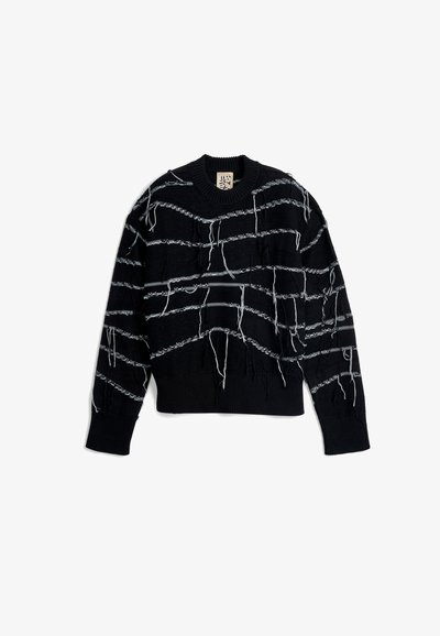 Black knit sweater with a crew neck, featuring irregular white horizontal stripes and loose threads for texture and detail.