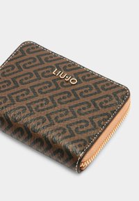 Portafoglio marrone con zip, caratterizzato da un motivo testurizzato e logo in tonalità oro. Il design include cuciture di contrasto e una chiusura con zip liscia.