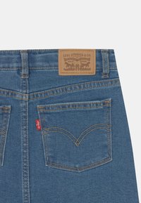 Blå denimjeans med en texturerad yta, med en l�äderlapp vid midjebandet och en klassisk böjd fickdesign.