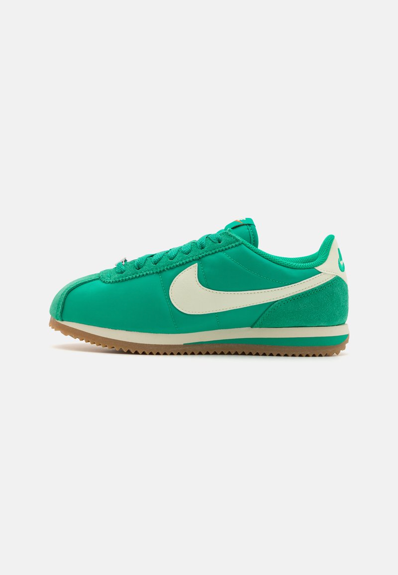 Zapatilla deportiva verde con un upper sintético suave, acentos de ante, logo Swoosh crema y una suela de goma texturizada.