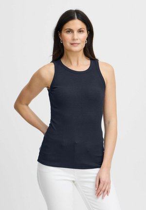 Navy ärmelloses Tanktop aus glattem, elastischem Material mit Rundhalsausschnitt, figurbetonter Form und minimalen Nähten. Trägt es mit weißen Hosen.