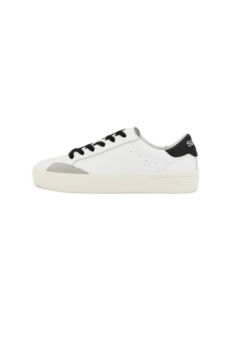 Sneakers bianchi con accenti neri, dettagli in suede grigio sulla punta, lacci neri piatti e suola in gomma testurizzata. Design minimalista.