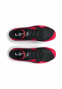 Black and red athletic shoes with a textured upper, flat laces, and white sole. Features branding on the sides and inside of the tongue.