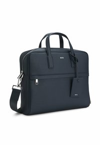 Granatowa skórzana aktówka z dwoma uchwytami, odpinanym paskiem na ramię, srebrnymi elementami metalowymi oraz zawieszką z nazwą marki. Gładka tekstura.