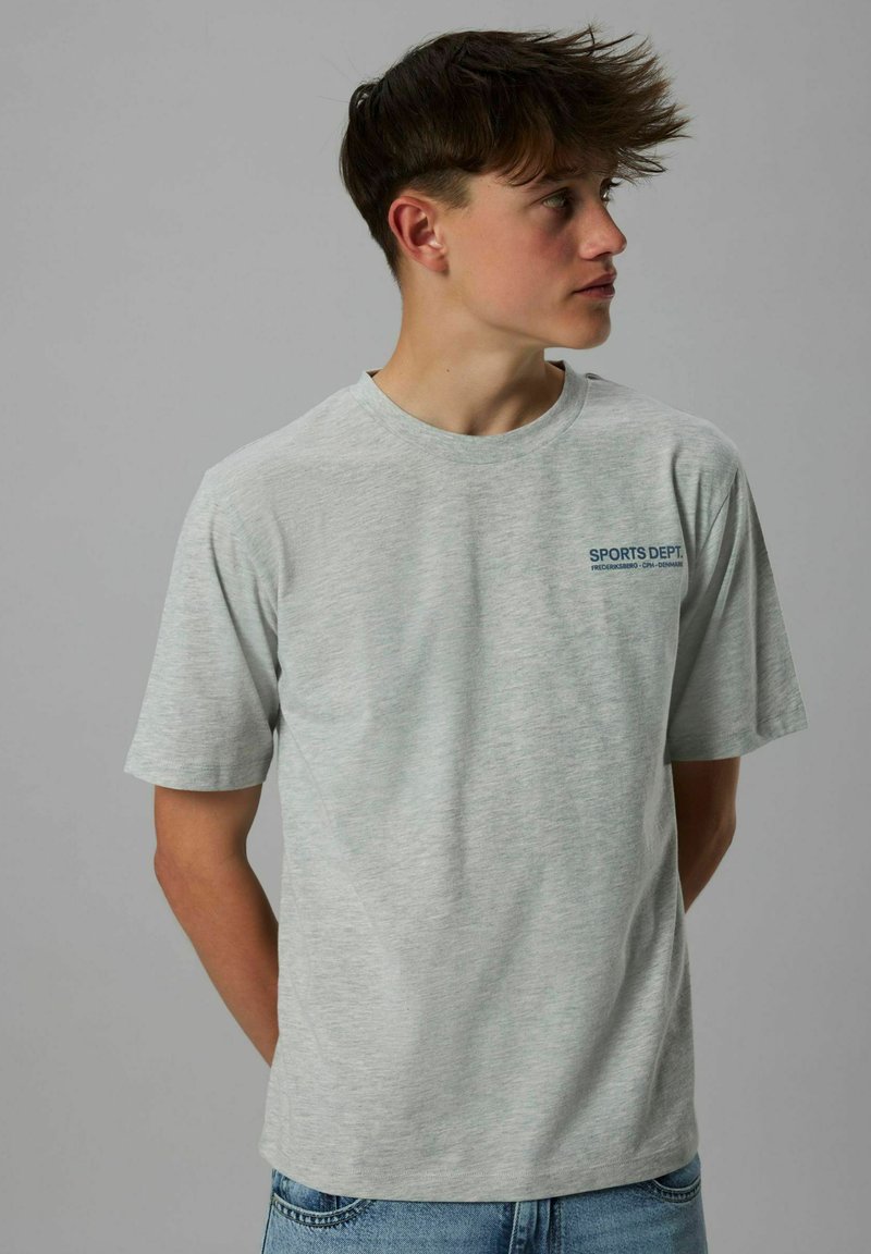 Lys grå bomulds t-shirt med korte ærmer, har en rund halsudskæring og et blåt "SPORTS DEPT." logo trykt på venstre brystområde.