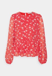 Blusa rossa a fiori con maniche lunghe e trasparenti, scollatura rotonda e vita a peplo. Presenta piccoli fiori bianchi e rosa su uno sfondo a pois.