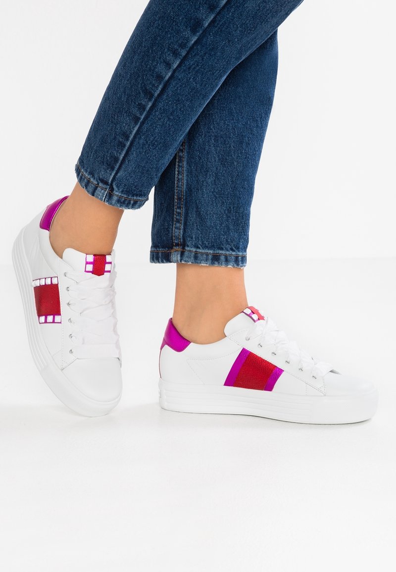 Baskets blanches avec des accents fuchsia et rouges. Matière en cuir lisse avec un panneau texturé et une semelle plate. Design à lacets, rayures sur les côtés.