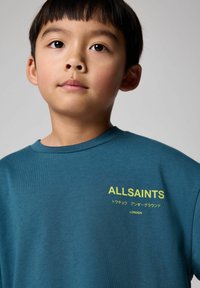 Teal bomulds T-shirt med rund hals, med gul "ALLSAINTS" tekst og ekstra grafik på fronten, glat tekstur.