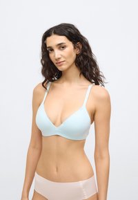 Σουτιέν ανοιχτού γαλάζιου χρώματος με ρίγες, βαθύ ντεκολτέ, λεπτές ρυθμιζόμενες τιράντες και λεία υφή. Συνδυάζεται με ανοιχτό ροζ εσώρουχο.