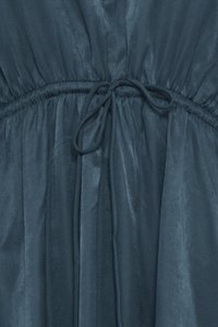 Tissu bleu foncé froncé avec un cordon noué créant un effet taille cintrée sur un vêtement.