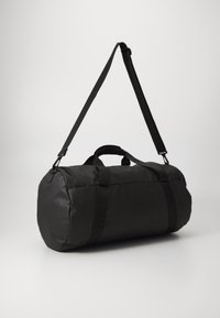 Sac de sport noir en tissu lisse et durable. Dispose de deux poignées et d'une bandoulière amovible, avec un design arrondi et des coutures discrètes.