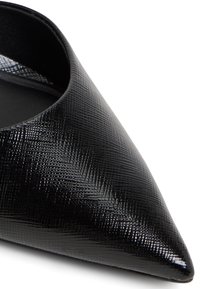 Černá boty s špičatou špičkou vyrobené z texturovaného syntetického materiálu s hladkým interiérem. Vyznačuje se štíhlým, minimalistickým designem a ostrou siluetou.