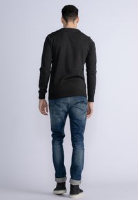 Dark gray long-sleeve sweater with a crew neck, paired with blue jeans featuring a faded wash and cuffed hems, worn with black ankle boots.