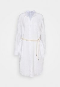 Abito camicia in lino bianco con maniche lunghe, colletto, bottoni frontali e una cintura color crema legata in vita. Sfondo semplice per mettere in risalto l'abito.