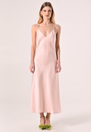 Satinkleid, hellrosa Farbe, V-Ausschnitt, dünne doppelte Träger, bodenlang. Das Modell trägt schlichte angenähte grüne Blumen-Heels.