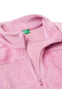 Růžová fleecová zipová bunda s vysokým límcem, vyšitým srdíčkem a měkkou texturou. Obsahuje zelenou etiketu uvnitř.