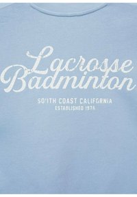 Felpa azzurro chiaro con una texture morbida, caratterizzata da testo bianco in stile usurato: "Lacrosse Badminton South Coast California Fondato nel 1978."