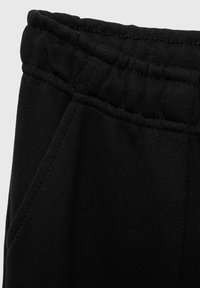 Schwarze Jogginghosen mit einem elastischen Bund und seitlichen Taschen, hergestellt aus einem weichen, strukturierten Stoff mit sichtbaren Nähten.
