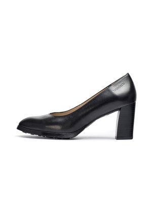 Zapato de tacón alto de cuero negro con punta redondeada, textura suave y tacón grueso con estrías verticales. Logo grabado en el lateral.