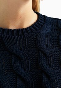 Granatowy sweter dziany z teksturowanym wzorem warkocza, ściągaczem na dekolcie i luźnym krojem, wykonany z miękkiego, oddychającego materiału.