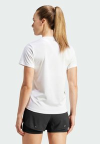 Kurzarmhemd in Weiß, hergestellt aus leichtem Stoff, kombiniert mit schwarzen Shorts. Verfügt über einen runden Ausschnitt und eine glatte Textur.