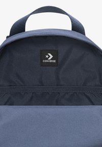Σακίδιο πλάτης σε ναυτικό μπλε με υφή, που διαθέτει επάνω λαβή και μαύρο λογότυπο CONVERSE μέσα στην κύρια θήκη.