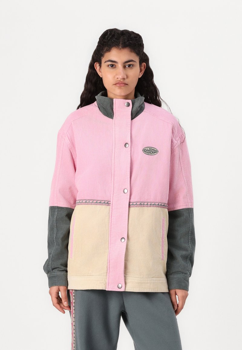 Corduroy jack met een roze bovenkant, beige onderkant en grijze mouwen. Heeft een hoge kraag, drukknoopsluiting en decoratieve stiksels.