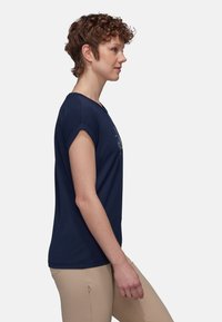 Granatowa koszulka polo z krótkim rękawem, okrągłym dekoltem, z prostym wzorem z przodu, wykonana z miękkiego materiału bawełnianego.