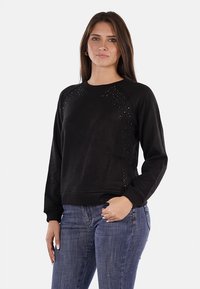 Felpa nera con scollo e polsini a costine. Presenta strass decorativi sulle spalle. Realizzata in tessuto morbido e strutturato.