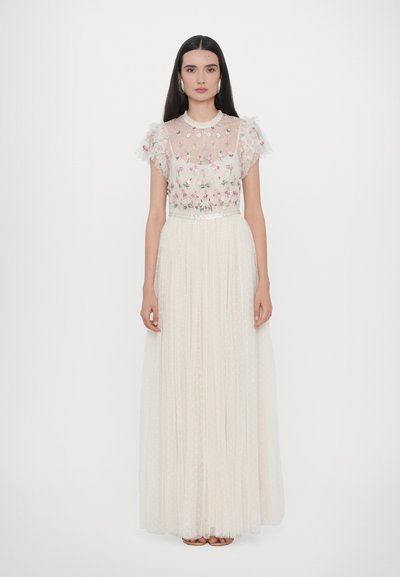 Robe blanche avec un corsage en dentelle florale transparente et une jupe plissée, ornée de délicates manches à volants et d'une ceinture en satin.