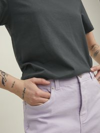 Camiseta de manga corta gris oscuro combinada con pantalones cortos de mezclilla en un suave lavanda, con bolsillos frontales y detalles de hardware metálico.