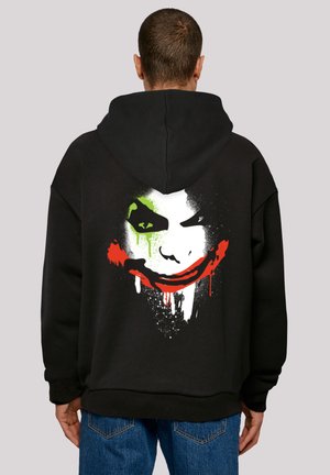 Black hoodie featuring a large graphic of a character's face with green accents, red mouth, and dripping details printed on the back.