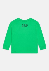 Langärmliges grünes T-Shirt. Baumwollmaterial mit Rundhalsausschnitt und GAP-Logo in Schwarz auf dem oberen Rücken. Einfaches Design, keine Muster.