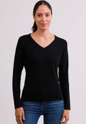 Schwarzes Langarm-Oberteil mit V-Ausschnitt, aus weichem Stoff gefertigt. Verfügt über eine figurbetonte Passform, glatte Textur und minimalistische Akzente. Getragen mit blauen Jeans.