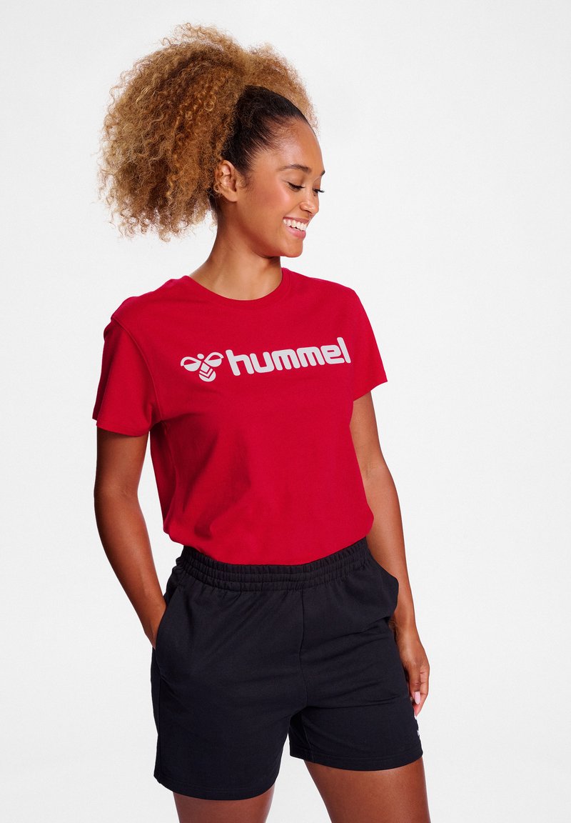 Rød bomulds T-shirt med hvid "hummel" logo, kombineret med sorte shorts med elastisk talje. Enkel design, korte ærmer og afslappet pasform.