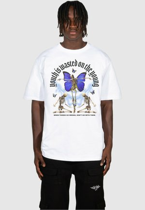 Hvid bomuld t-shirt med grafisk tryk af en blå sommerfugl og knogler, med tekst der siger "ungdommen er spildt på de unge."