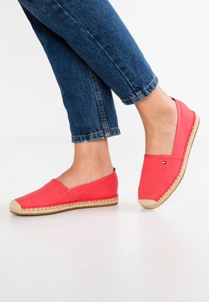 Rode canvas instapschoenen met een zool van juten touw en een stoffen logotag, gecombineerd met opgerolde blauwe spijkerbroek.