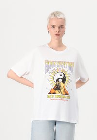 White cotton t-shirt with short sleeves and a relaxed fit. Features a colorful graphic with a yin-yang symbol, sun, and mountain design.